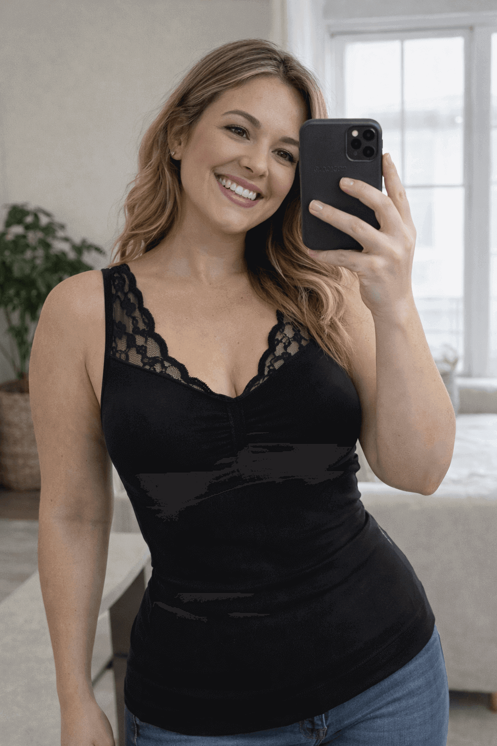 Woman taking a selfie wearing the Vellomi Black SculptCami with lace detailing in a home setting.