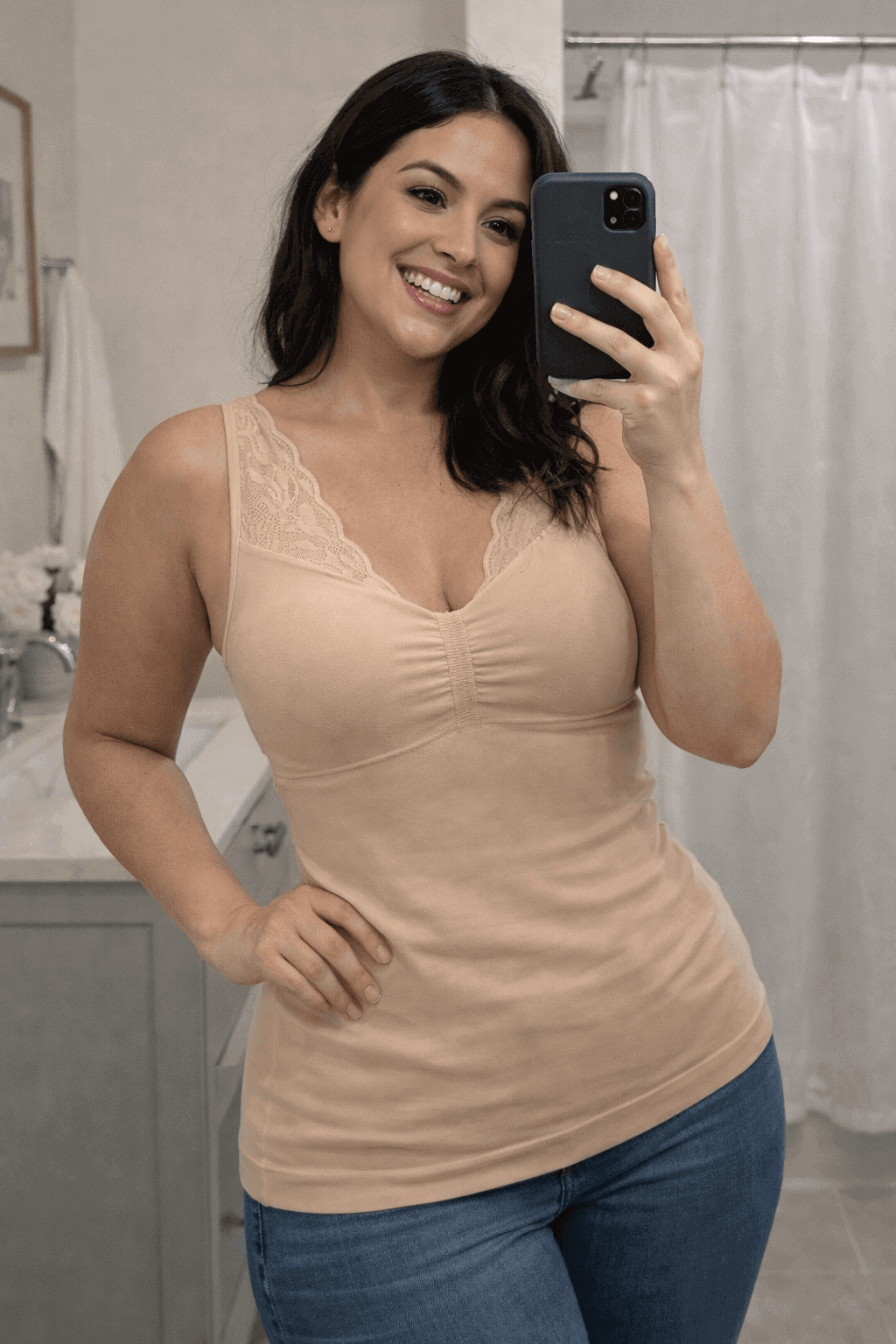 Woman taking a mirror selfie wearing the Vellomi Nude SculptCami with lace detailing and blue jeans in a bathroom.